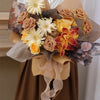 A floral arrangement featuring dried roses and yellow flowers wrapped with a silky organza ribbon roll.