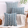 A set of three blue and white geometric patterned throw pillows displayed on a wooden surface.