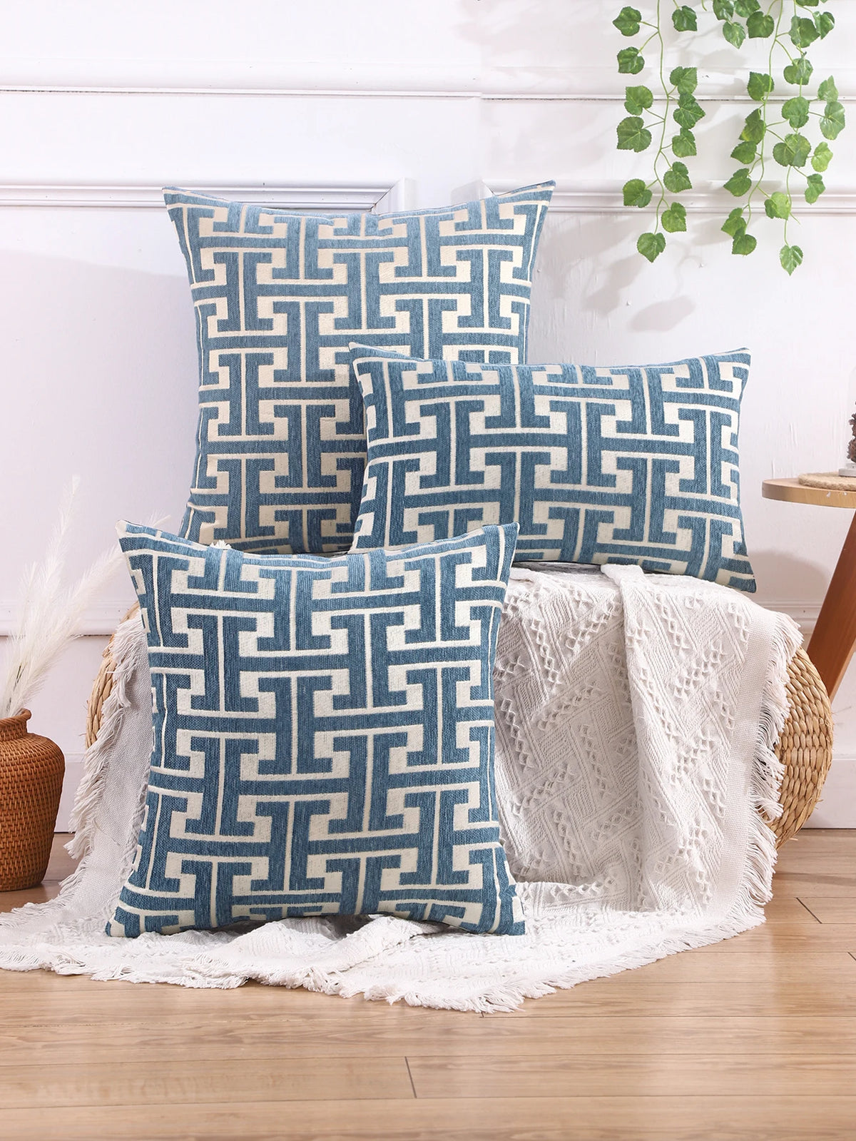 A set of three blue and white geometric patterned throw pillows displayed on a wooden surface.