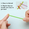 A hand holds a bright green plastic sewing needle with a large eye, demonstrating its ease of threading.