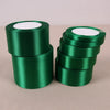 A stack of green satin ribbon rolls with white centers for crafting and decoration.