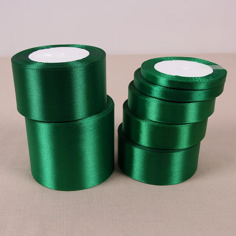 A stack of green satin ribbon rolls with white centers for crafting and decoration.