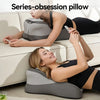A woman is using a gray series-obsession pillow for neck and back support while relaxing on a couch.