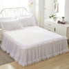 White princess lace bed skirt set with white bedding and headboard in a bright bedroom setting