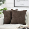 Two brown corduroy patchwork pillow covers resting on a white sofa with a light green plant in the background.