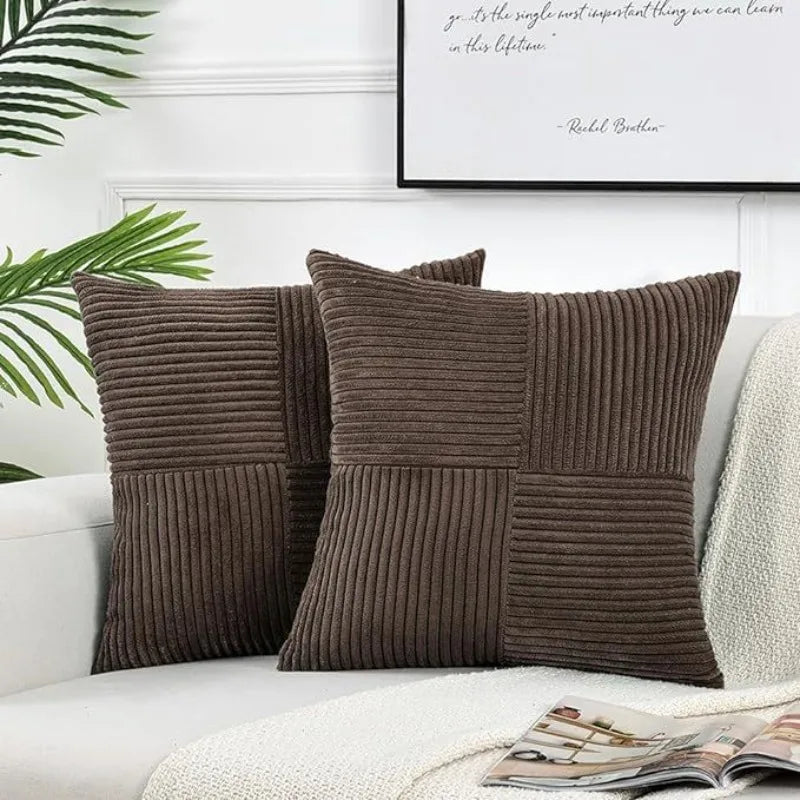 Two brown corduroy patchwork pillow covers resting on a white sofa with a light green plant in the background.