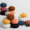 A stack of colorful plush pumpkins in various shades including blue, pink, orange, and green.
