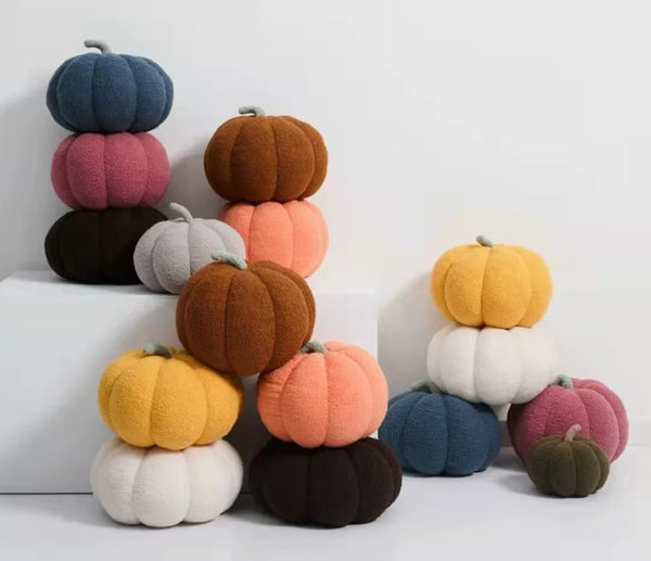 A stack of colorful plush pumpkins in various shades including blue, pink, orange, and green.