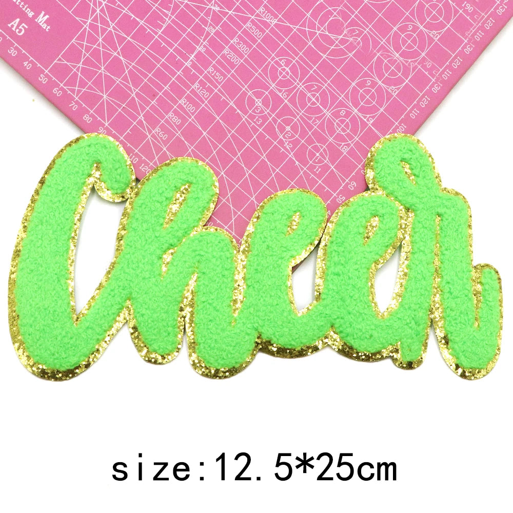 Green glitter letter patch spelling cheer on pink fabric