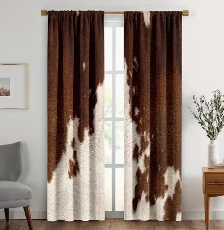 A set of two brown and white cow print curtains hanging in a doorway.