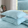 Light blue embroidered cotton quilted pillow cover set stacked on a bed