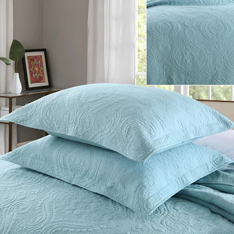 Light blue embroidered cotton quilted pillow cover set stacked on a bed