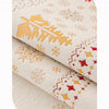 Close-up of beige fabric with gold and red snowflake patterns, showing a rolled sofa seat cover.