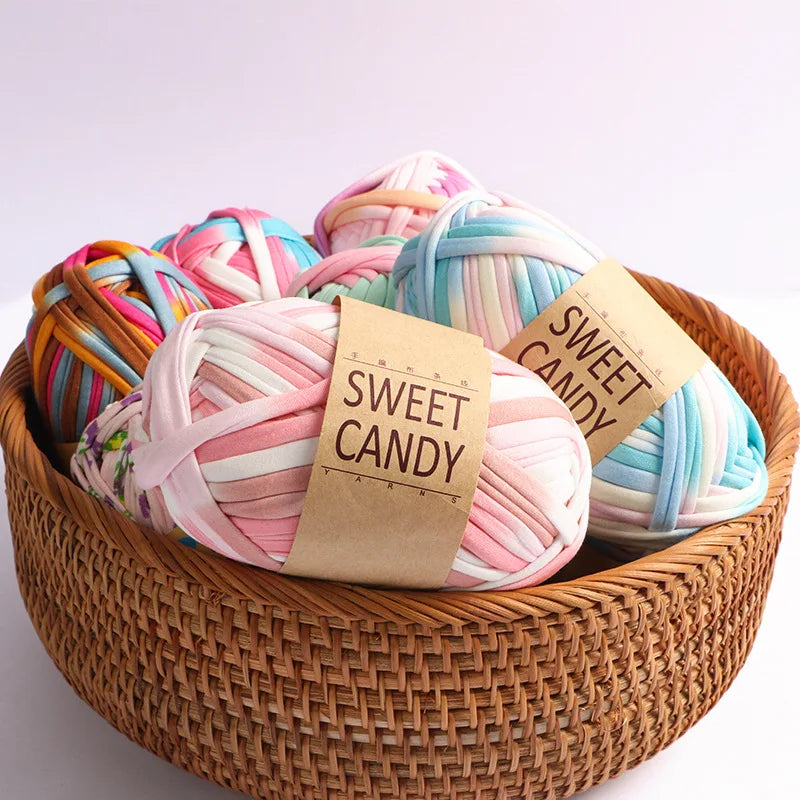 A basket filled with hand-dyed pink and blue striped yarn skeins labeled Sweet Candy