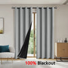 Gray blackout curtains hanging on a rod in a bright room with a wooden door visible.