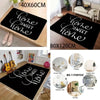Black geometric rug with white script text on a wooden floor.