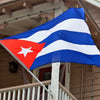 A vibrant blue and white striped flag of Cuba is displayed outdoors.