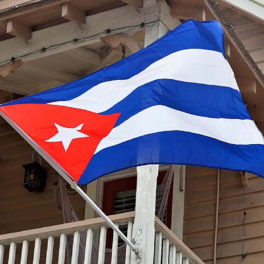 A vibrant blue and white striped flag of Cuba is displayed outdoors.
