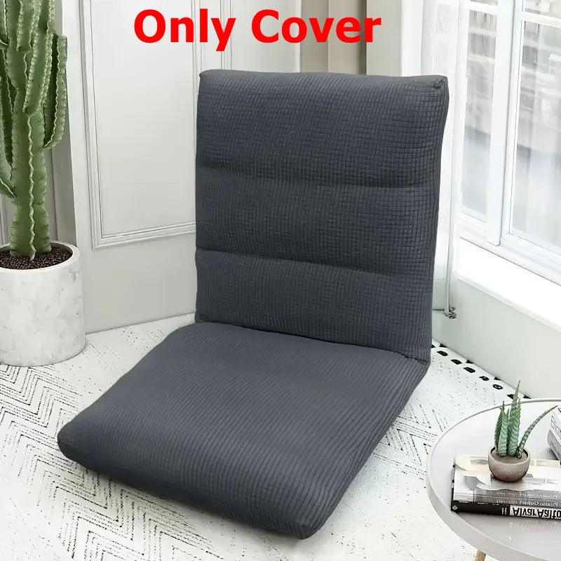 A dark gray folding tatami seat cover placed on a white floor, next to a window and a potted cactus.