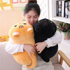 A woman is holding a yellow soft cat plush pillow cushion and a black soft cat plush pillow cushion.
