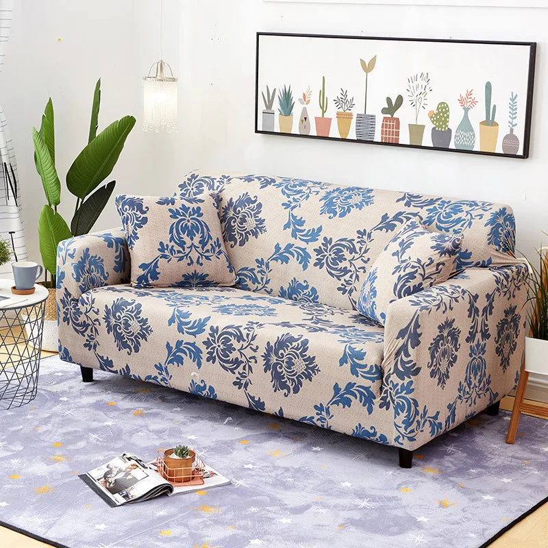 A light blue patterned stretch sofa slipcover displayed on a floor, with a framed botanical print on the wall.