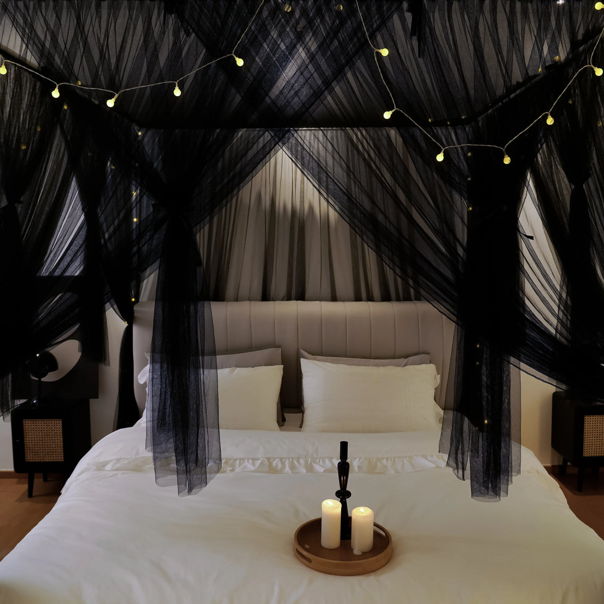 An elegant mosquito net bed canopy featuring sheer black netting draped over a white bed.