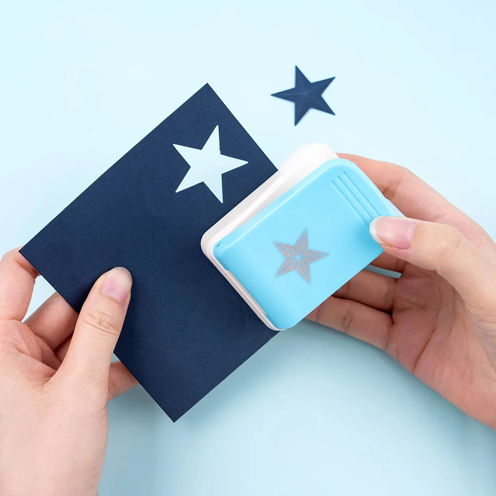 A hand holds a light blue embossing tool against a dark blue card with a star design.