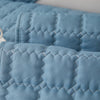 Close-up of a light blue quilted anti-slip sofa cover with a plush texture.