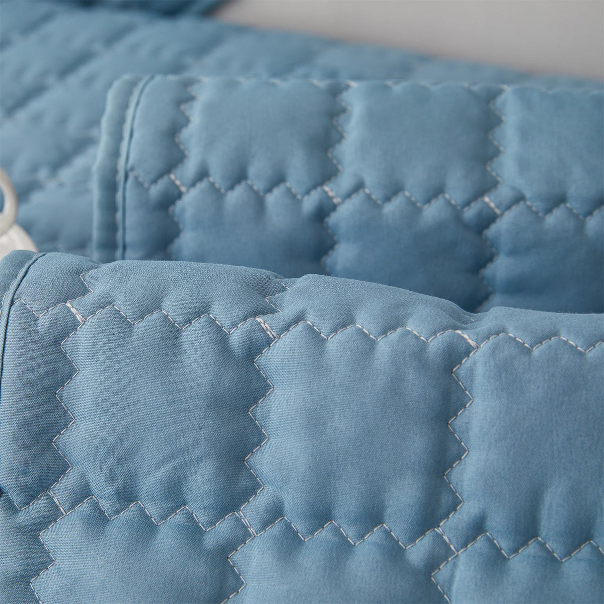Close-up of a light blue quilted anti-slip sofa cover with a plush texture.