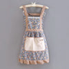 A floral pattern kitchen apron with adjustable straps and a cream-colored pocket, displayed on a hanger.