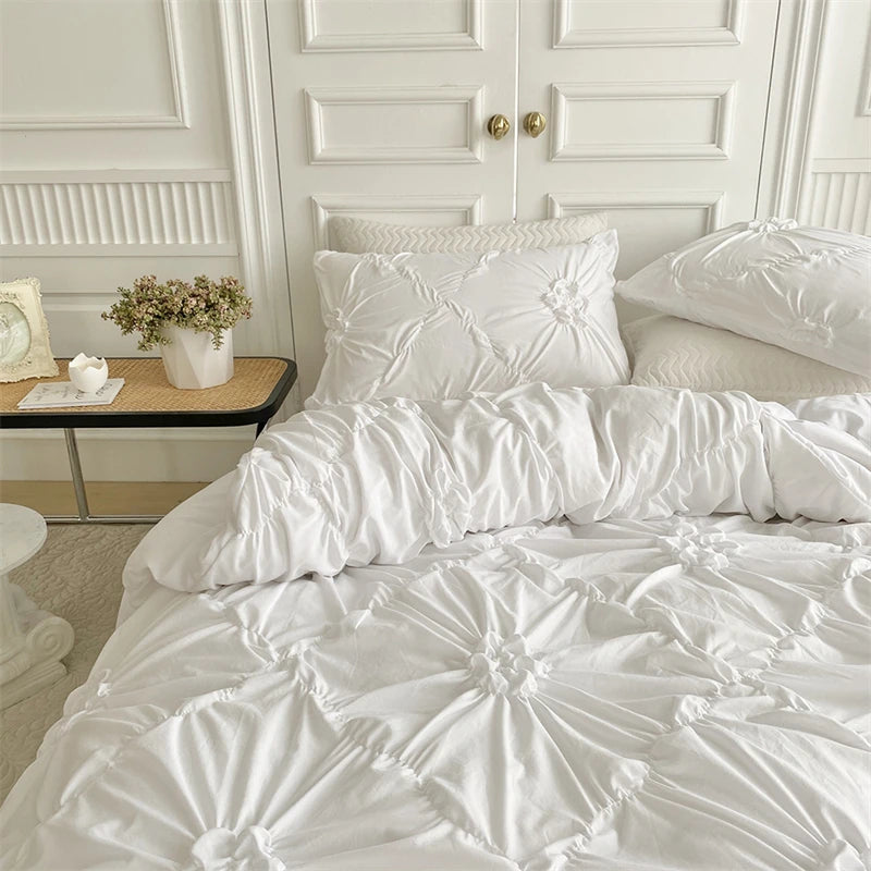 White quilted duvet cover set displayed on a bed with white paneled doors and a small potted plant.