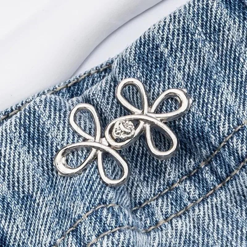 Silver adjustable leaf clover waist tightener attached to blue denim fabric.