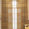 A pair of beige hollow perforated curtains with ornate gold patterns hanging in a doorway.