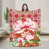 A strawberry shortcake plush throw blanket featuring a pink strawberry character and red checkered fabric.