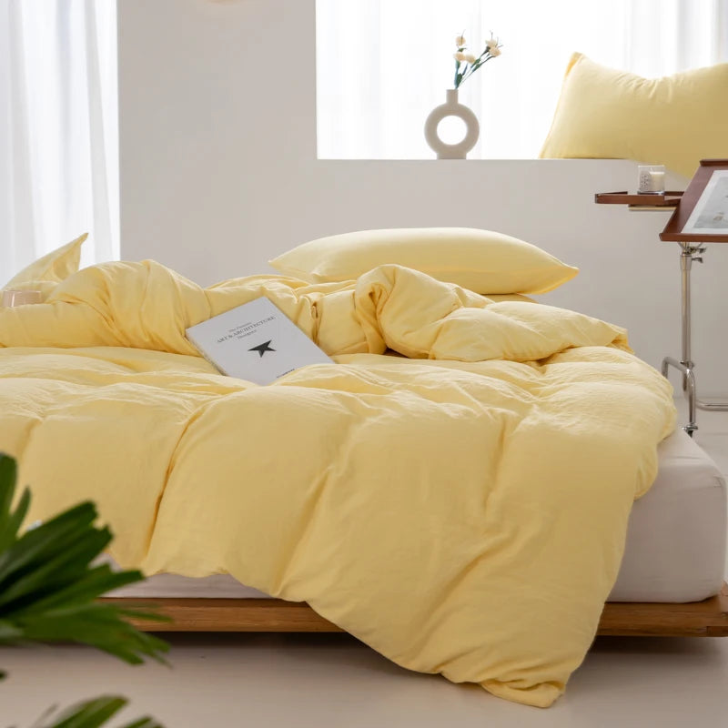 A bright yellow minimalist duvet cover is displayed on a bed with white bedding and natural wood framing.