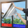 A hand is applying a one-way mirror window film to a glass pane, demonstrating its installation.