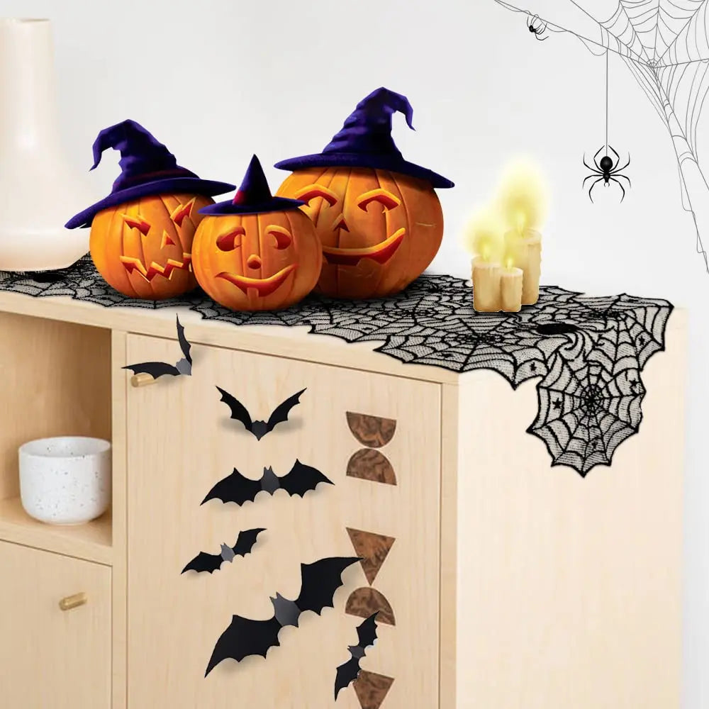 A Halloween display featuring a black lace spider web table runner with carved pumpkin decorations and witch hats.