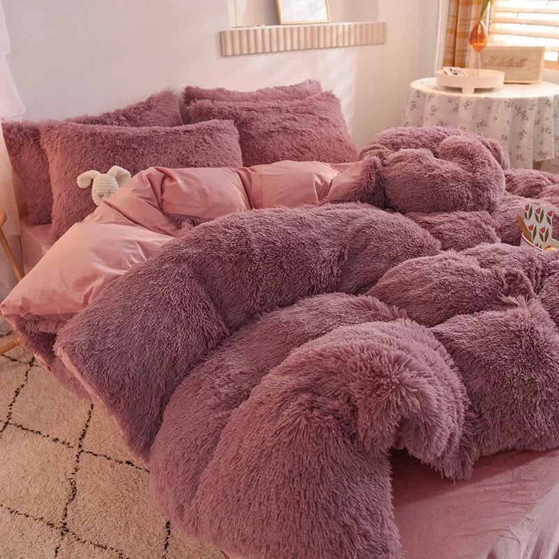 A pile of fluffy mauve mink velvet bedding and pillows on a bed.