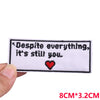 White embroidered patch with black text Despite everything it's still you and a red heart symbol