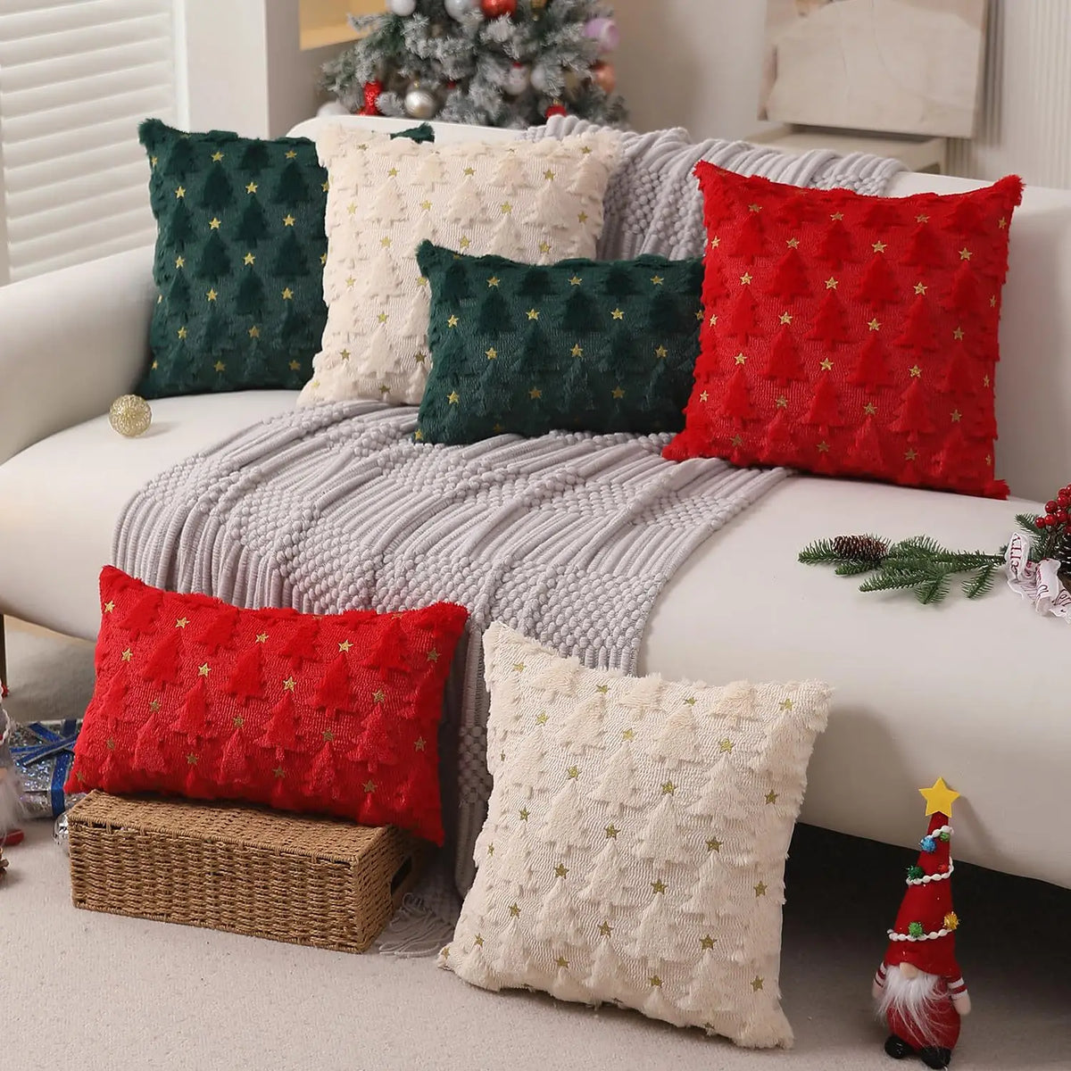 A collection of red and green knitted Christmas cushion covers displayed on a white sofa.
