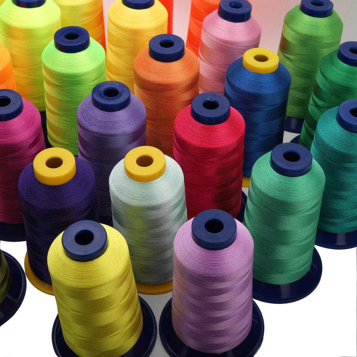 A collection of brightly colored polyester embroidery thread spools in various shades including yellow, green, orange, pink, 