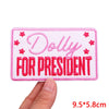 Pink embroidered patch with the text Dolly for President on a white background