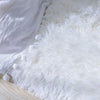 A fluffy white shag rug placed on a wooden floor next to a white fabric item.