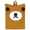 A brown cartoon bear face design on a tan throw blanket.