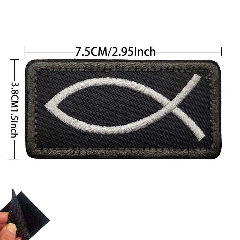 A black embroidered patch featuring a white cross design.