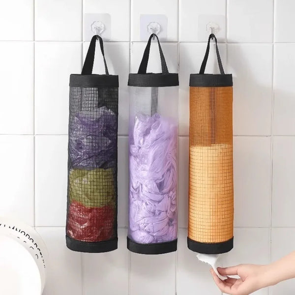 Three hanging mesh trash bags in purple, green, and orange are displayed on a white tiled wall.