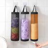 Three hanging mesh trash bags in purple, green, and orange are displayed on a white tiled wall.