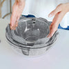 Hands are placing reusable felt pot protectors into a clear glass bowl for kitchen storage.