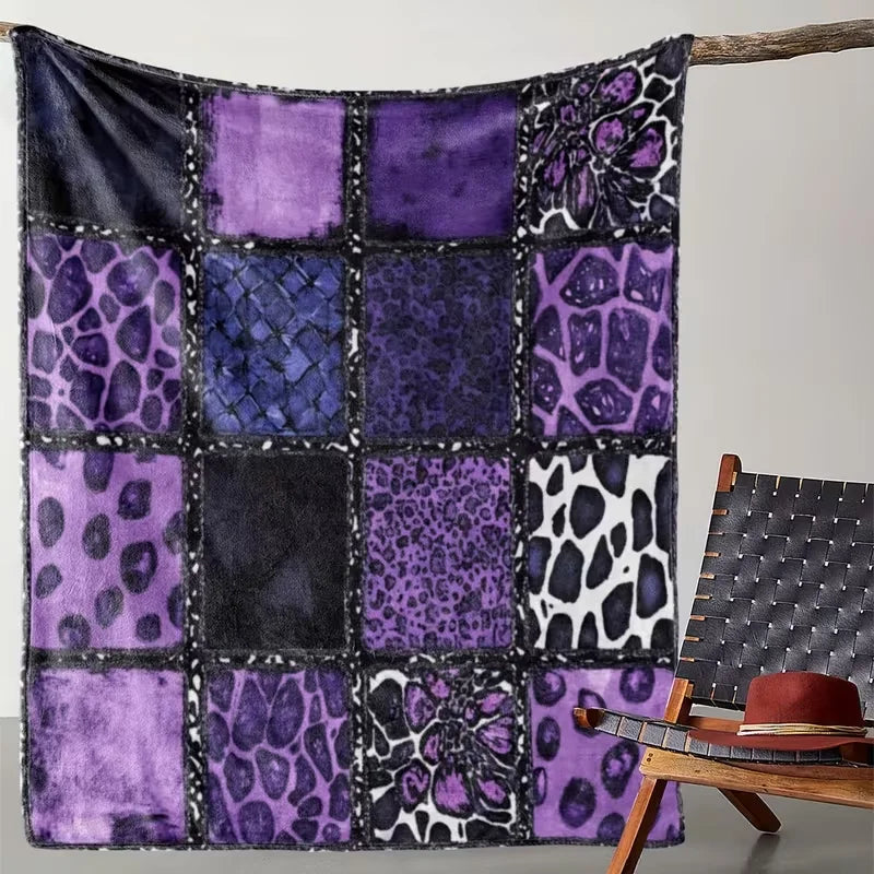 A square quilt blanket featuring a patchwork design with purple and black leopard print fabric hanging on a wooden stick.