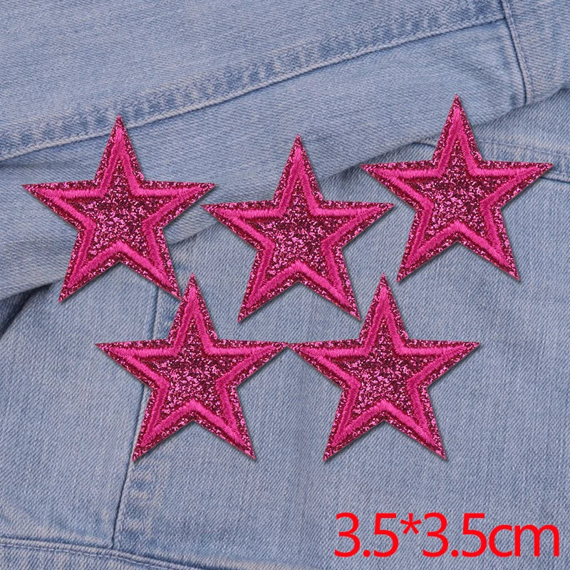 Five pink glitter star patches embroidered on a denim fabric